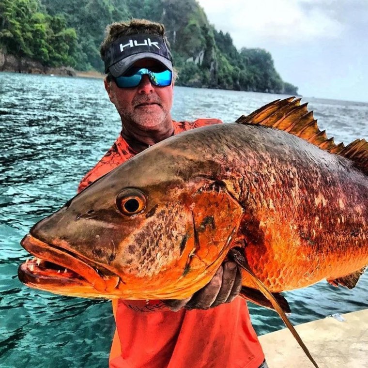Captain Bo Johnson holding a large cubera snapper close to the camera.