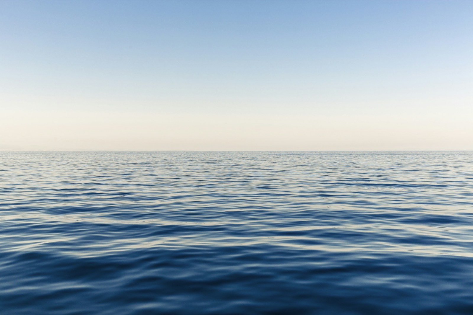 Open ocean meeting a warm, pale horizon.